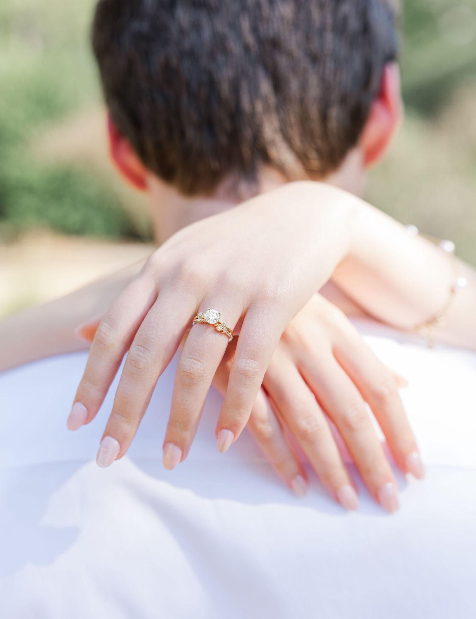 Close-up of Emma's engagement ring as her hand rests on Dylan's shoulder