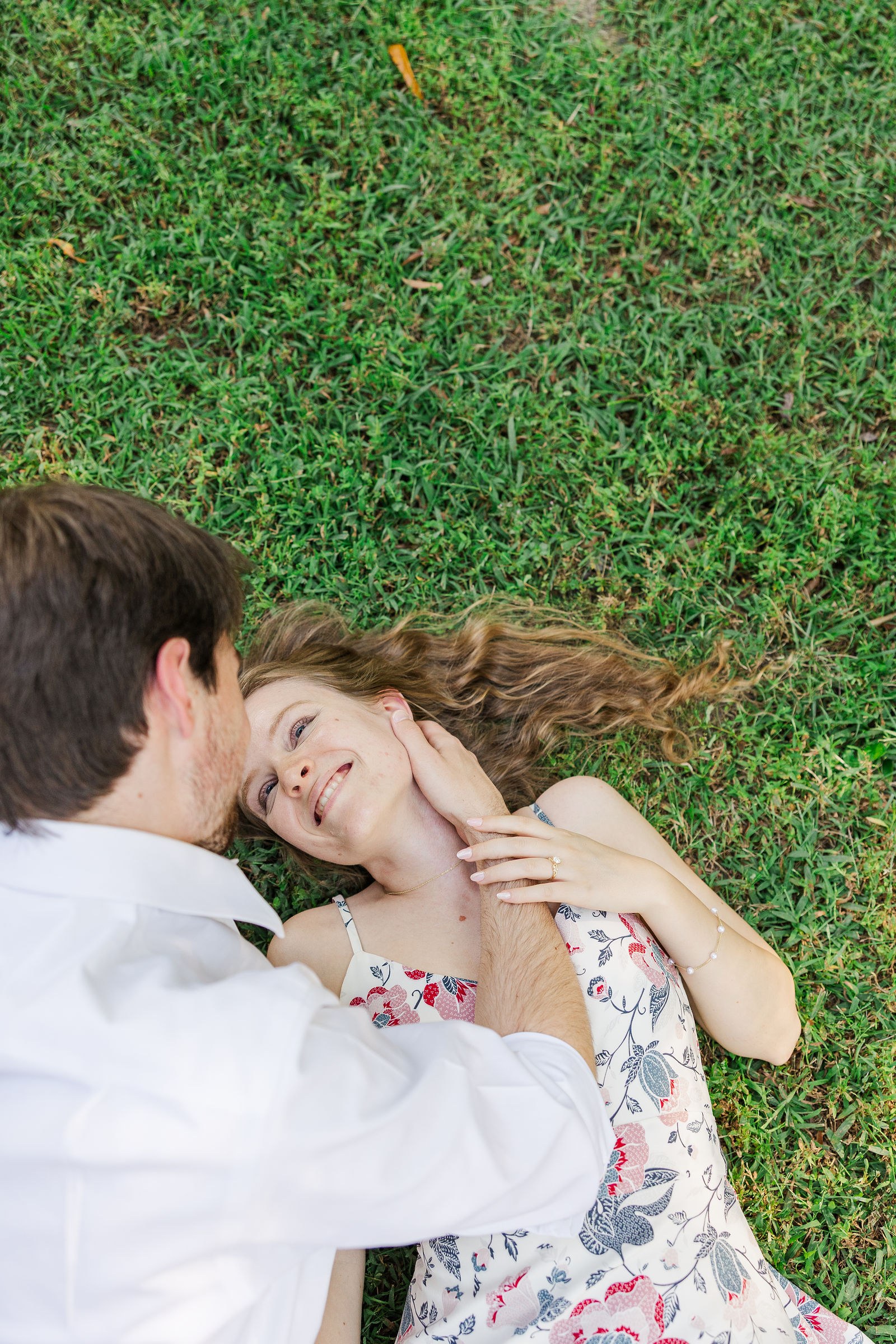 Dylan and Emma lying in the grass laughing during their North Atlanta garden engagement session