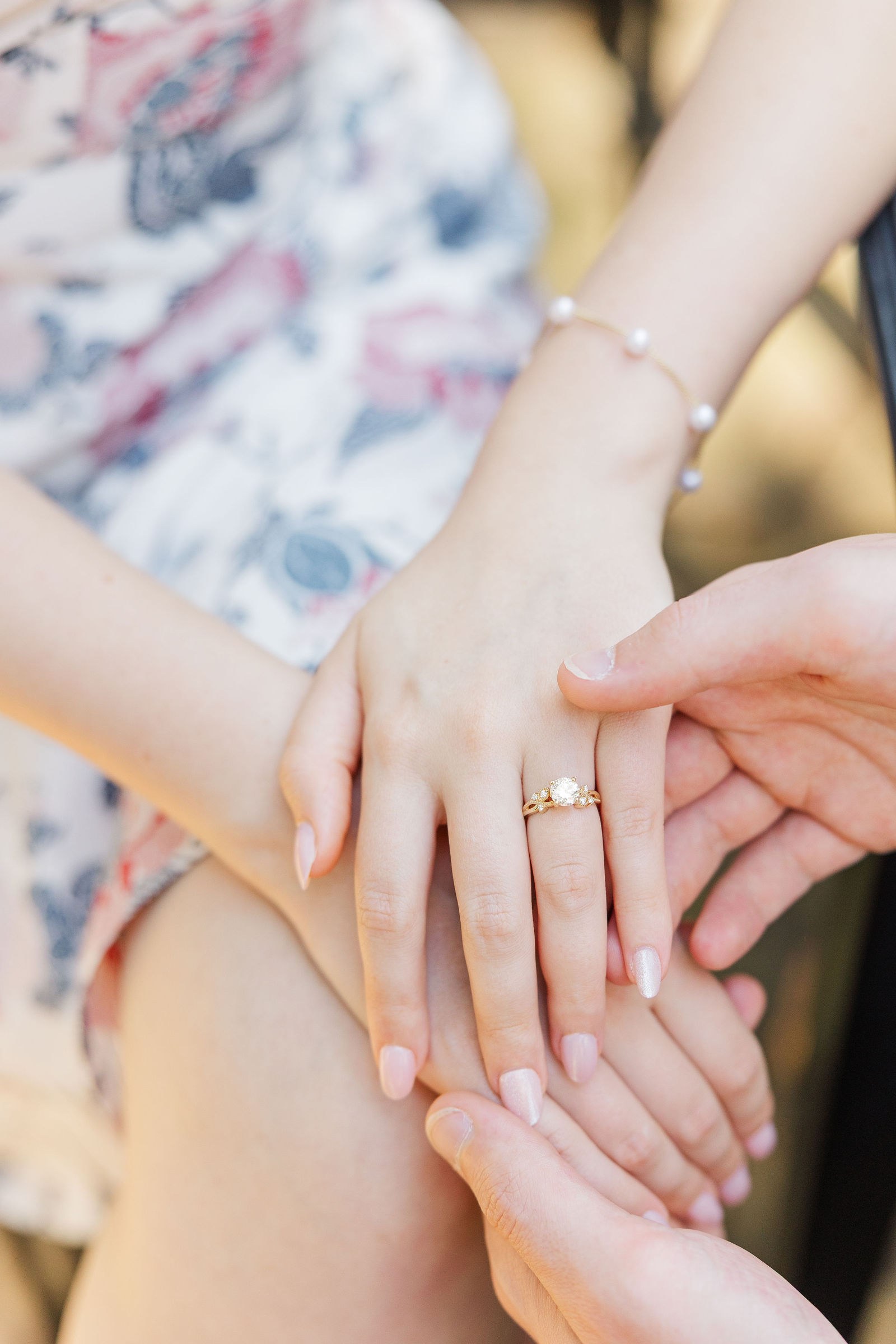 Close-up of the couple's hands showing Emma's engagement ring and pearl bracelet